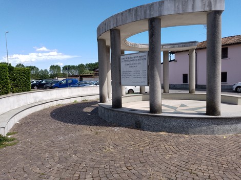 Monumento ai caduti di Mignete, struttura circolare con colonne e pavimentazione in pietra.