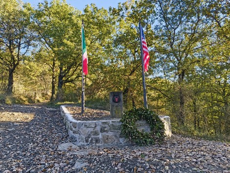 Monumento alla Red Bull, dedicato ai caduti, con bandiere italiana e americana e una corona di alloro.