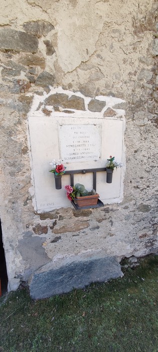Lapide commemorativa dedicata a Meneghetti, Romeo e Scaramuzzino, montata su una parete di pietra.