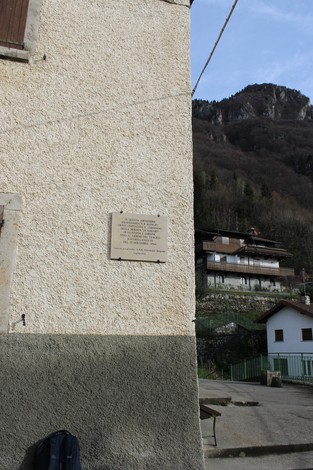 Lapide commemorativa del comando della brigata 24 maggio su una parete di un edificio in un contesto montano.