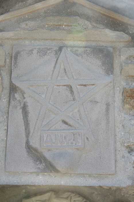 Dettaglio del "Tabernacolo di Valdonetto" con simbolo e incisioni su pietra. Architettura storica locale.