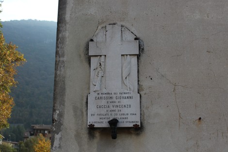 Lapide commemorativa dedicata a Caccia e Carissimi, posta su una parete con sfondo naturale.