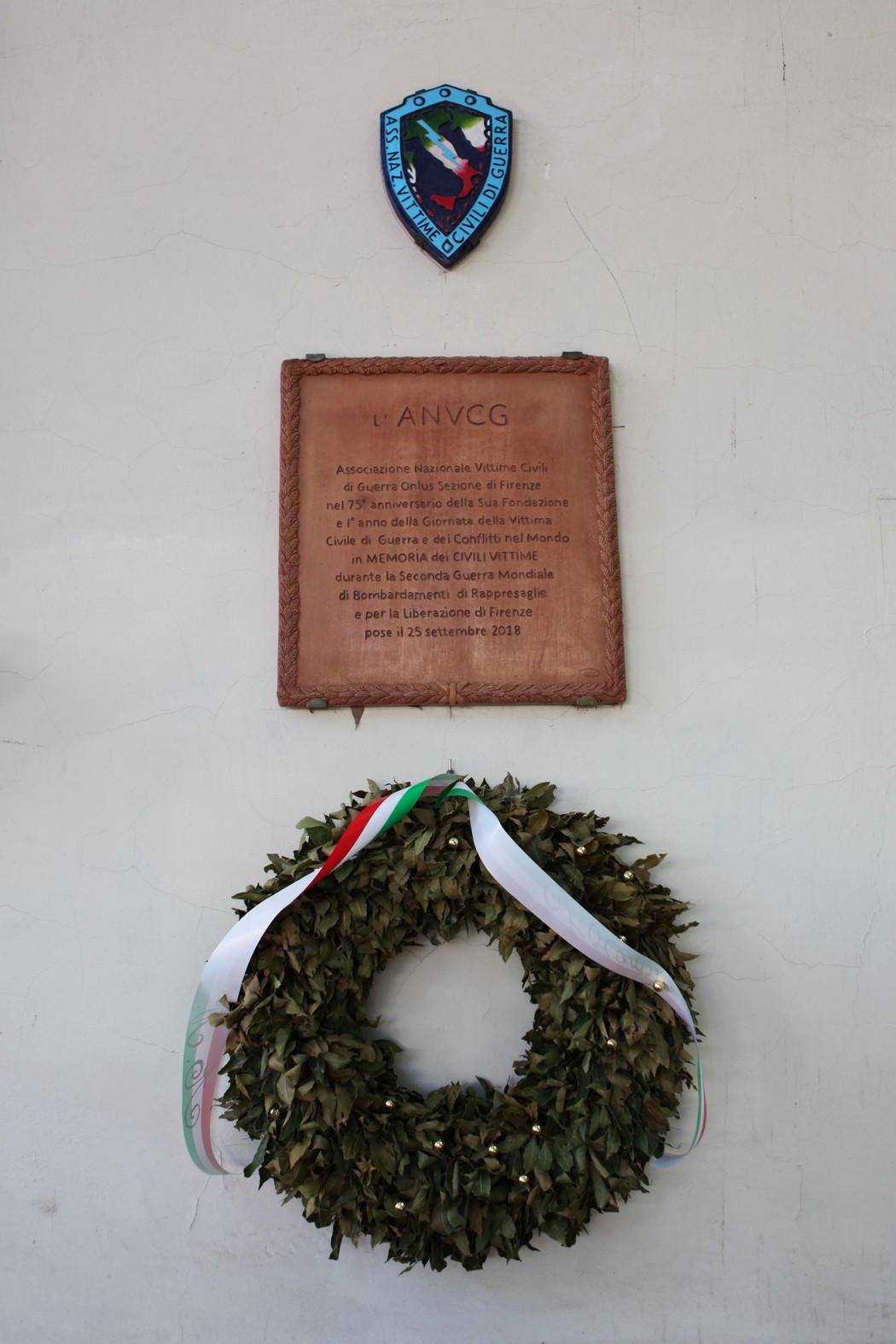 Lapide commemorativa dedicata alle vittime civili di guerra, con ghirlanda di alloro e simbolo dell'ANVCG.