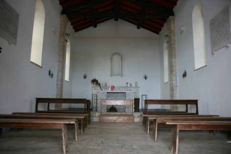 Interno della Chiesetta dei Partigiani del Pasquilio, con panche in legno e pareti semplici e luminose.