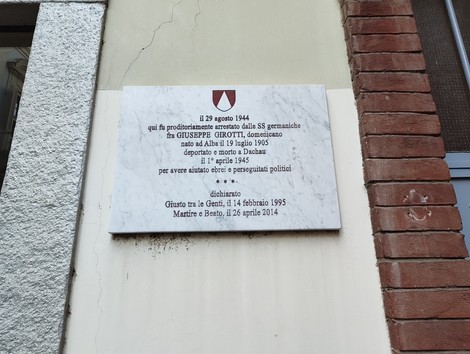 Lapide commemorativa dedicata a Giuseppe Girotti, vittima del regime. Situata su una parete di un edificio.