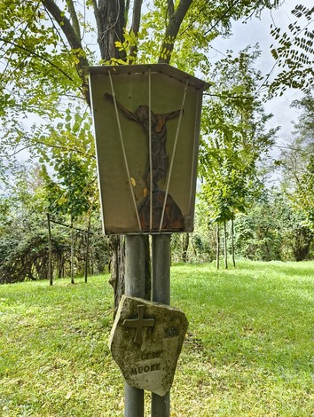 La Via Crucis di Casaglia con crocifisso e simboli religiosi immersi nella natura.