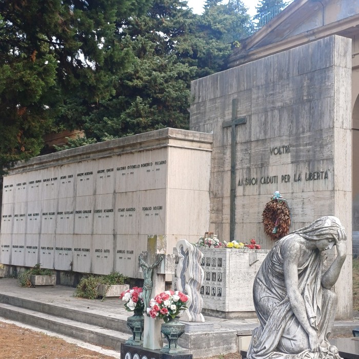 Sacrario in pietra con croce e iscrizione, loculi con fotografie e statua di donna china in lutto.