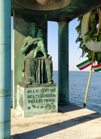 Monumento bronzeo dedicato alle vittime del Giudecca, affacciato su un paesaggio marino.