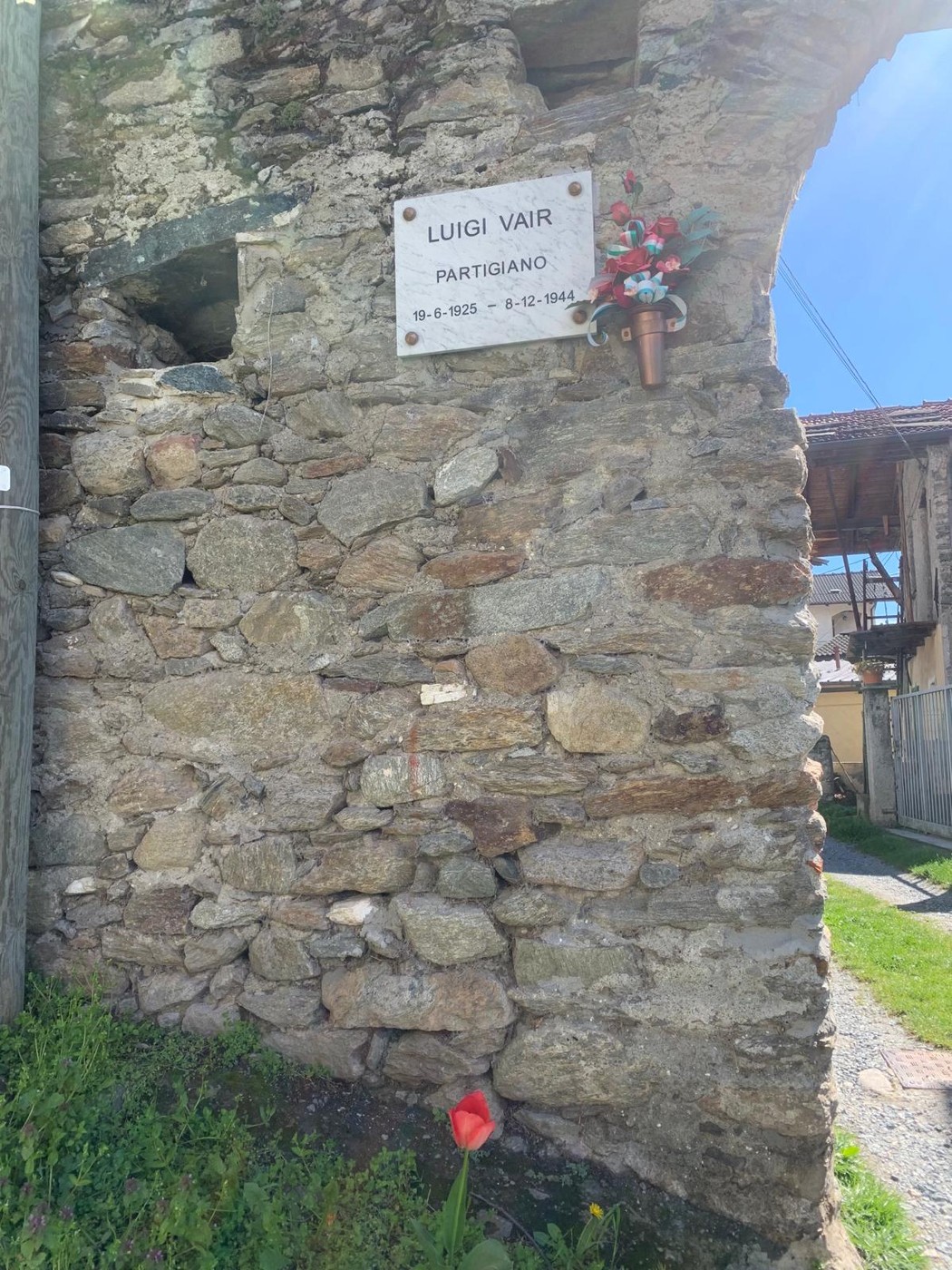 Lapide commemorativa dedicata a Luigi Vair, partigiano, situata in un antico muro di pietra.