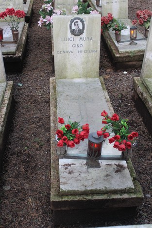 Tombe con lapidi commemorative decorate da fiori rossi e candele, dedicate ai caduti per la libertà.