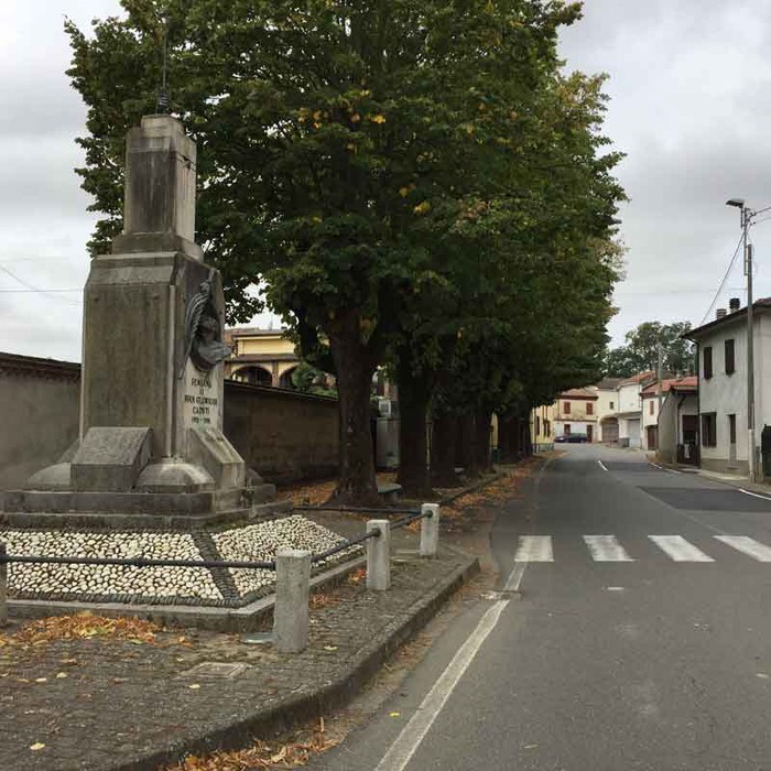 Monumento ai caduti di Semiana, posizionato lungo una strada, circondato da alberi e una zona residenziale.