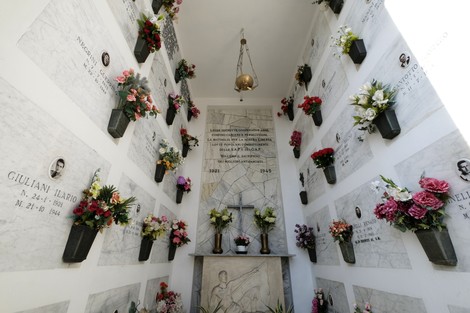 Interno del "Sacrario dei Partigiani di Castenaso" con targhe commemorative e fiori freschi. Atmosfera di rispetto e memoria.