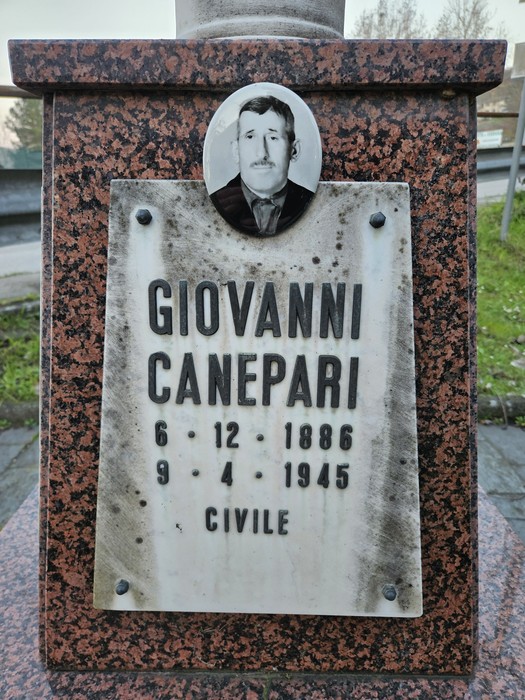 Cippo commemorativo con foto e iscrizioni dedicato a Giovanni Canepari, situato in un'area verde.