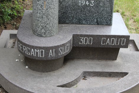 Monumento alla Divisione Acqui, commemorativo con iscrizioni e decorazioni, immerso nel verde.