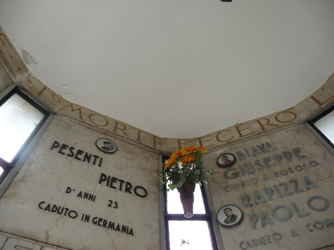 Sacrario ai caduti partigiani con incisi nomi e fiori in un'atmosfera di commemorazione e rispetto.