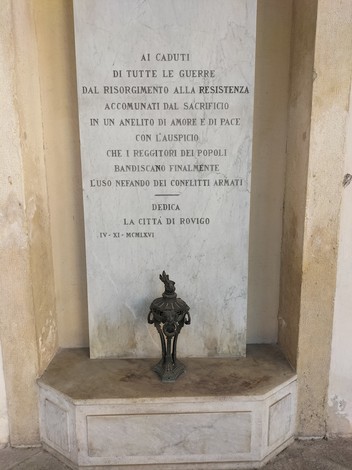 Lapide commemorativa dedicata alla pace, situata in un angolo di un edificio storico.
