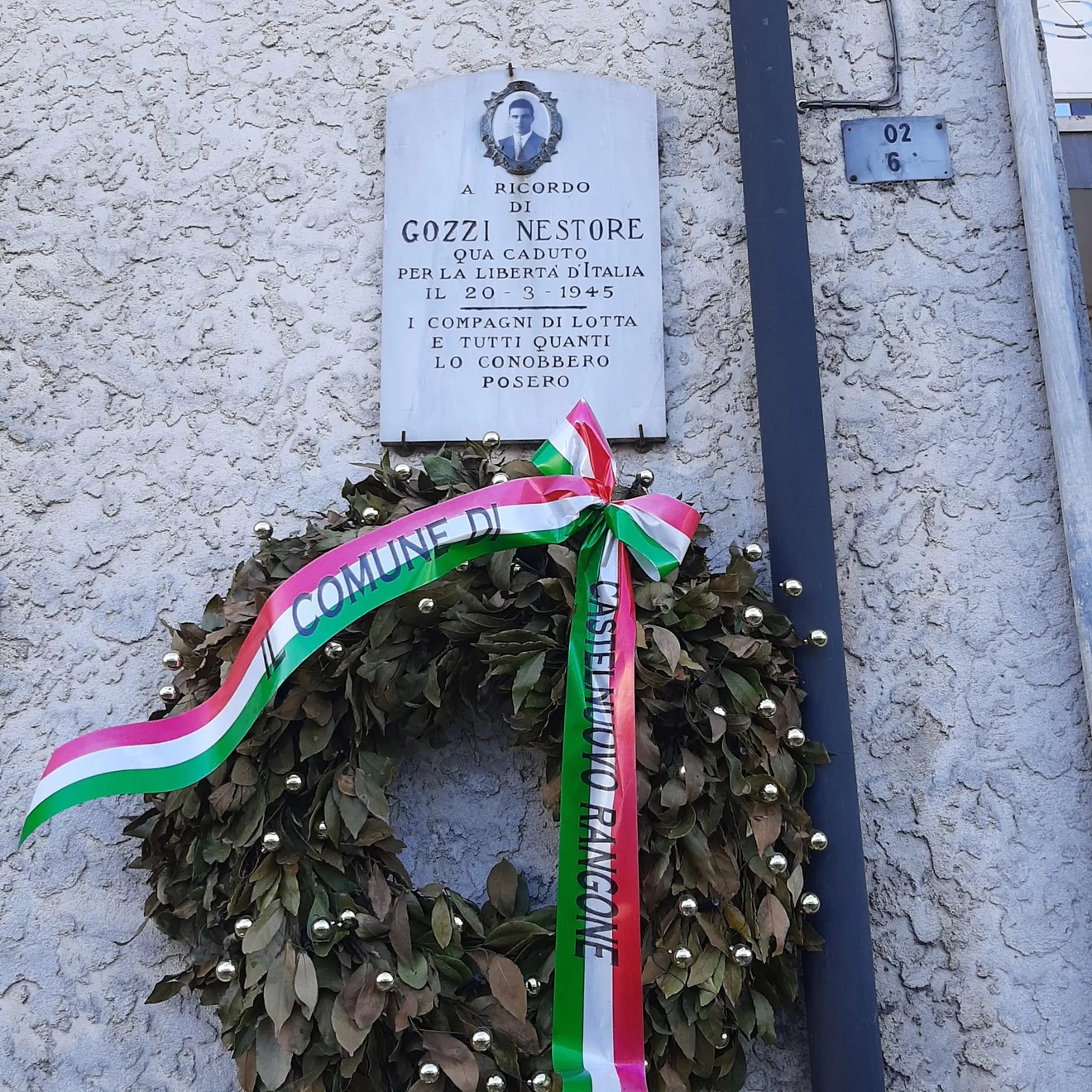 Lapide commemorativa con corona di fiori, dedicata a Gozzi Nestore per la libertà d’Italia.