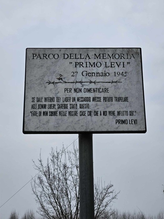 Cippo commemorativo dedicato agli internati e ai deportati, con riferimento a Primo Levi e alla memoria storica.