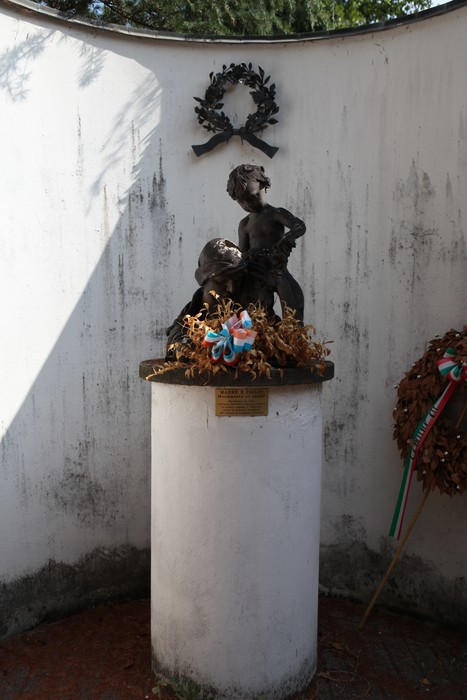 Monumento ai Caduti con statua commemorativa e decorazioni floreali, immerso in un'atmosfera di rispetto e memoria.