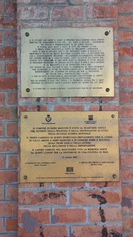 Lapidi commemorative delle Caserme Rosse, su muro di mattoni, con testi informativi sulla storia del luogo.