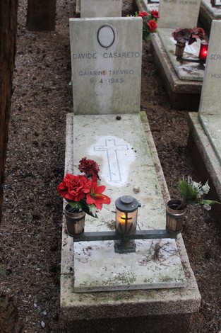 Tombe ornamentate con fiori e candele, dedicate ai caduti per la libertà in un cimitero memorativo.