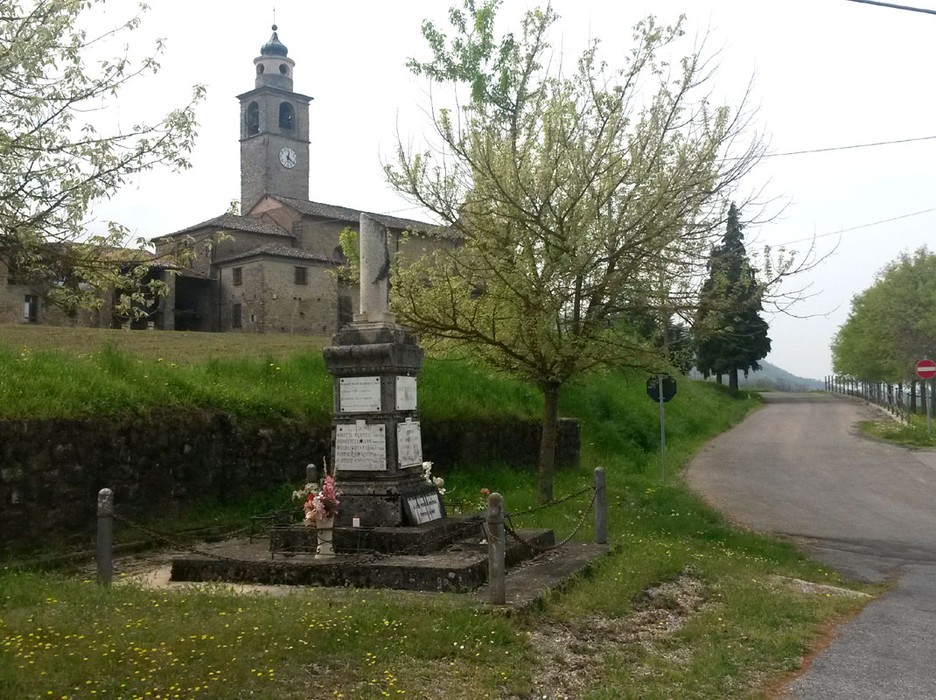 Monumento ai caduti di Val di Nizza, con chiesa e alberi che circondano l'area.