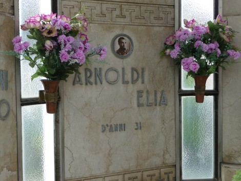 Sacrario dedicato ai caduti partigiani, con fiori e targa commemorativa di un caduto.