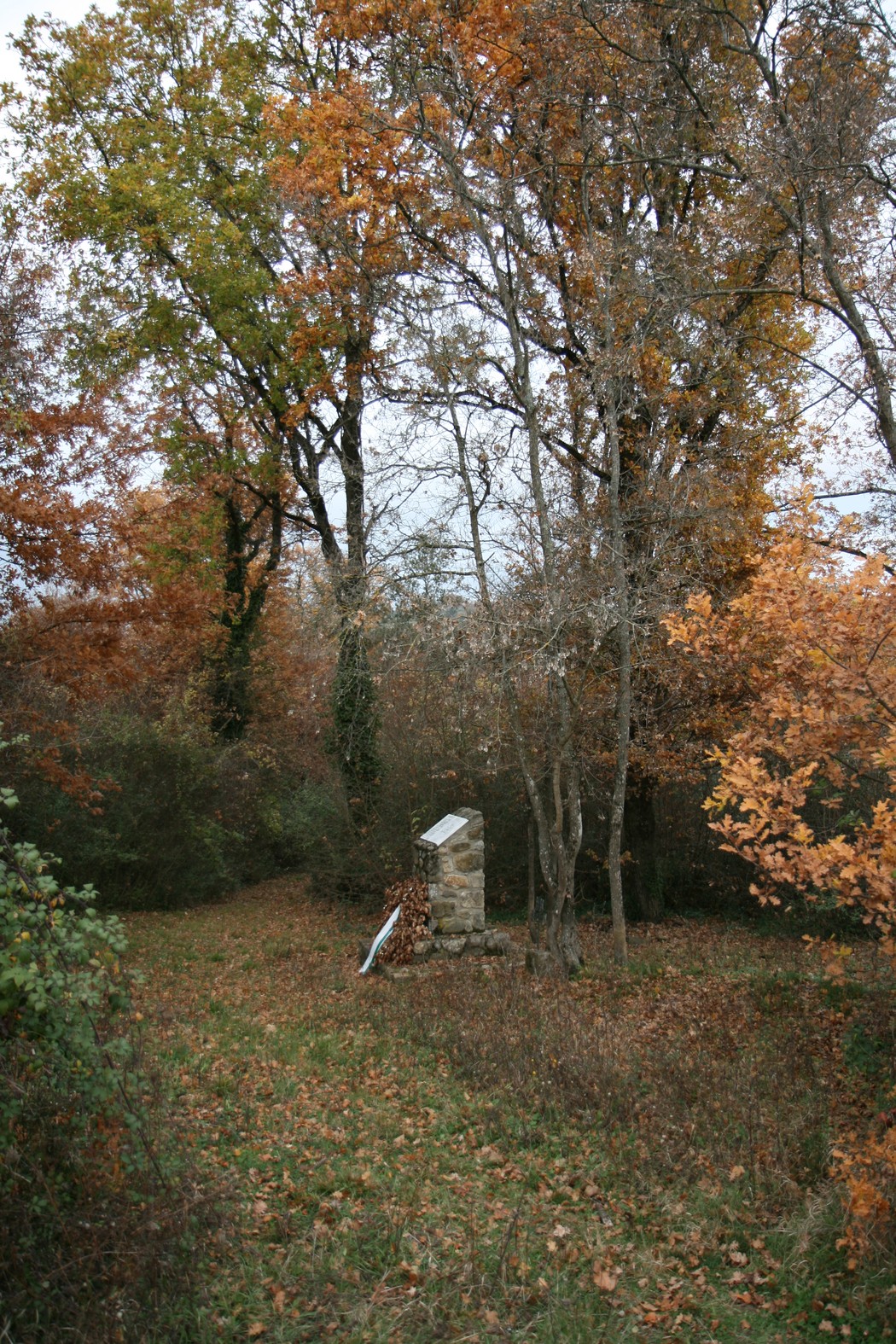 Cippo commemorativo in un bosco autunnale, dedicato alle vittime dell'eccidio di Pratale.