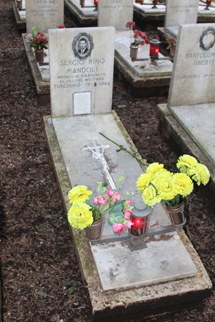 Tombe con fiori e candele commemorative dedicate ai caduti per la Libertà in un cimitero.