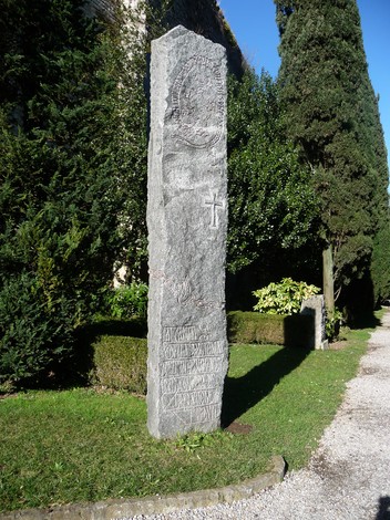 Monumento in pietra dedicato ai caduti della prigionia, circondato da alberi e aree verdi.