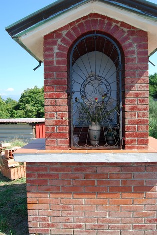 Tabernacolo in muratura dedicato alla famiglia Barucci, con decorazioni e grate in ferro lavorato.