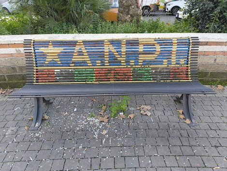 Panchina decorata con il simbolo dell'ANPI, rappresentando i valori della Resistenza. Elementi di colore vivace.