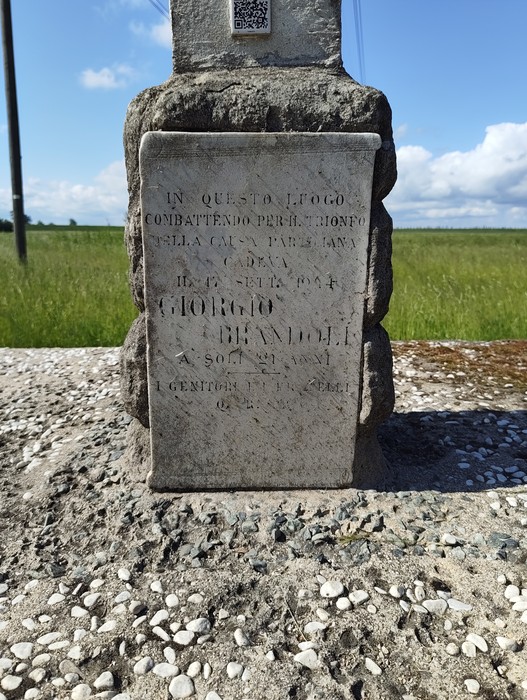 Cippo a Brandoli, monumento commemorativo in una vasta area verde, con nuvole nel cielo.
