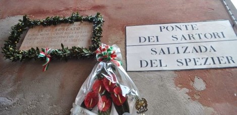 Lapide commemorativa a Borgato, decorata con un fascio di fiori e nastri tricolore.