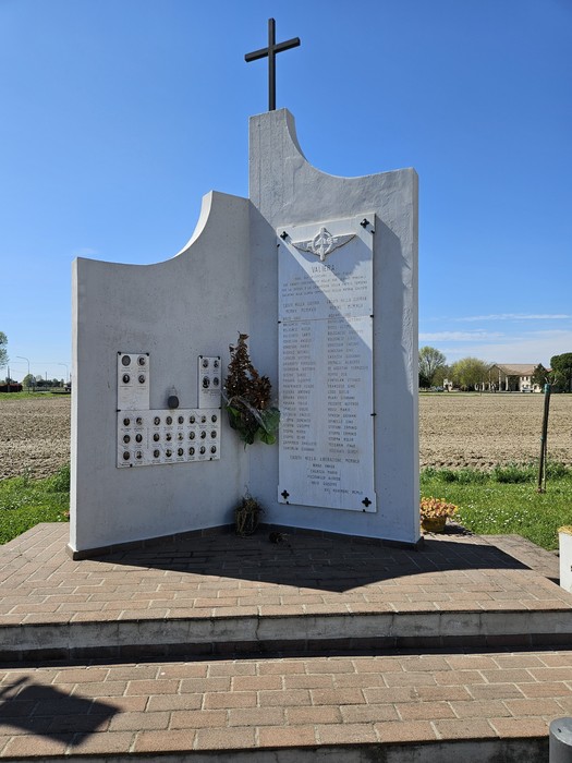 Monumento commemorativo ai Caduti di Valliera, con elenco di nomi e decorazioni floreali in un contesto rurale.