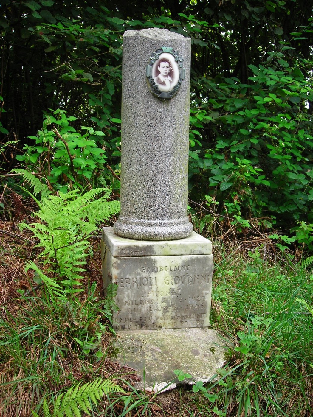 Cippo commemorativo dedicato a Giovanni Ferrioli, immerso nella natura circostante.