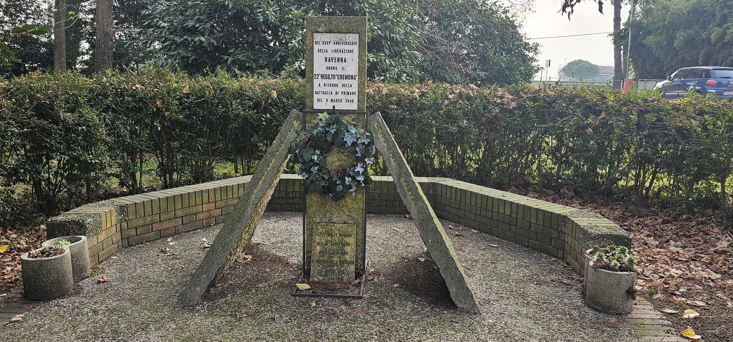 Monumento al "Cremona", dedicato alla memoria dei caduti, circondato da piante e un'area di commemorazione.