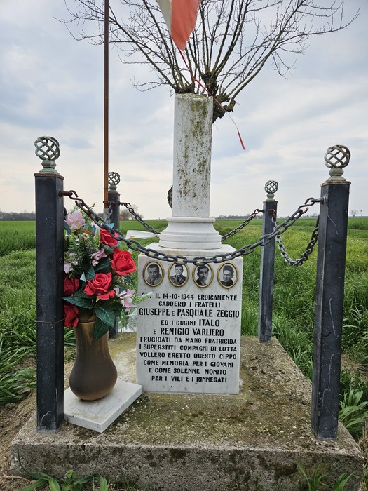 Cippo commemorativo dedicato a Giuseppe e Pasquale Zeggio e Eugenio Italo Varliero, con decorazioni floreali.
