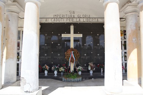 Sacrario commemorativo con croce, fiori e iscrizioni per i caduti in nome della libertà.