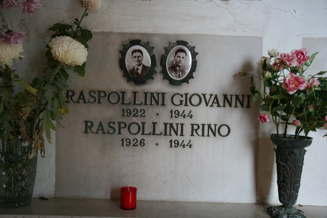 Sepolcro commemorativo delle vittime dell'eccidio di Pratale con fotografie e omaggi floreali.