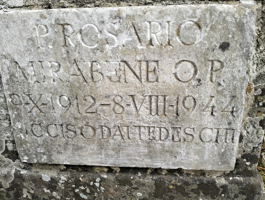 Cippo commemorativo a Mirabene con iscrizioni di memoria storica, in contesto naturale.