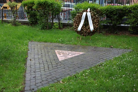 Monumento commemorativo per le vittime omosessuali, con un triangolo rosa e una corona di fiori.