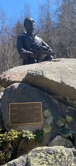 Monumento a Ilardi, con statua su roccia e placca informativa nel verde circostante.