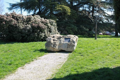 Masso antifascista situato in un parco con vegetazione e un sentiero di ghiaia che vi conduce.