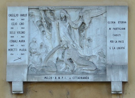 Lapide commemorativa ai partigiani con rilievi artistiche che rappresentano momenti storici di resistenza e lotta.