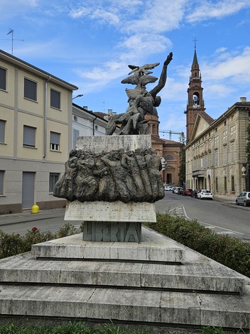 Monumento alla Resistenza con figure in bronzo e sfondo di edifici storici e cielo azzurro.