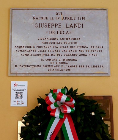 Lapide commemorativa dedicata a Giuseppe Landi, antifascista e partigiano, situata in un luogo pubblico.