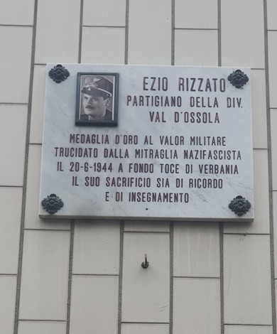 Lapide commemorativa in marmo dedicata a Ezio Rizzato, partigiano della Divisione Val d'Ossola, con foto e dettagli storici.