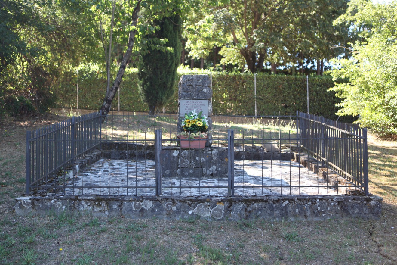 Cippo commemorativo a Francini, circondato da una recinzione e un giardino curato.