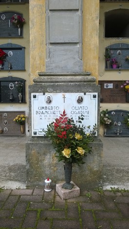Lapide commemorativa di Umberto Branchetti e Oliato Cigarini con fiori e lumino.
